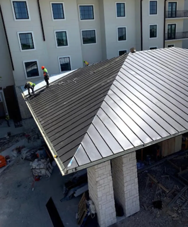 Crew installing standing seam metal roof panels on a commercial project in Cascade